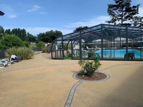 un pavillon avec une piscine dans une cour dans l'établissement Le parc des roselieres 40 Saint Hilaire de Riez, à Saint-Hilaire-de-Riez