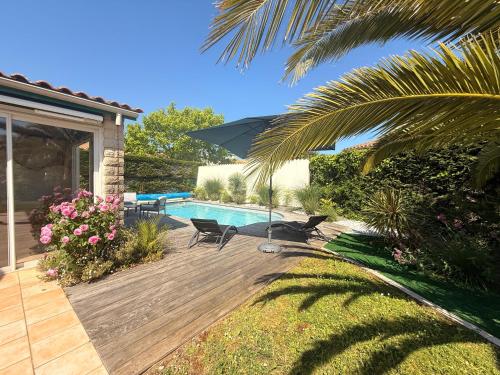 une arrière-cour avec une terrasse en bois et une piscine dans l'établissement Au bord de la piscine pres de la plage, à La Brée-les-Bains