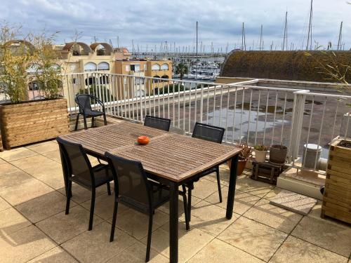 a wooden table and chairs on a balcony at Appt 80 m2 vue port avec baignoire balnéo in Gruissan