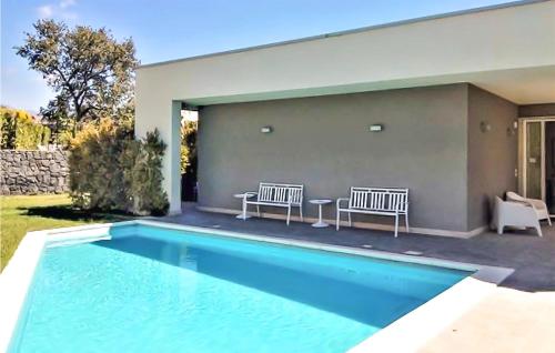 a swimming pool with two benches next to a house at 4 Bedroom Cozy Home In Mascalucia in Mascalucia