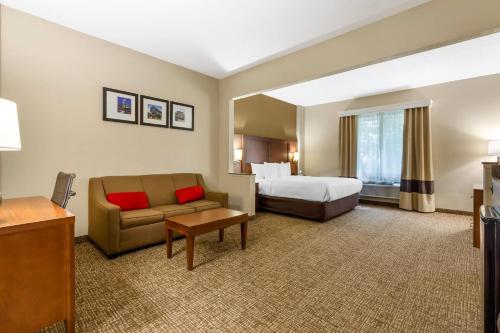 a hotel room with a bed and a couch at Comfort Suites Raleigh Walnut Creek in Raleigh
