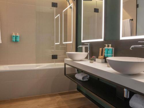 a bathroom with two sinks and a bath tub at Novotel Valencia Lavant in Valencia