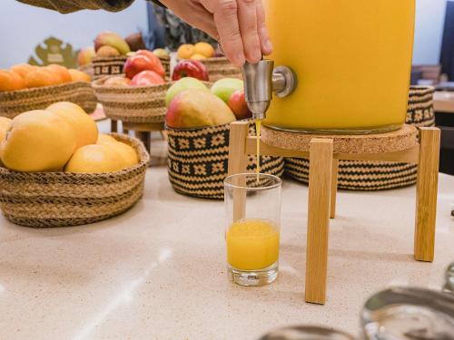 a person pouring an orange juice into a glass at Novotel Valencia Lavant in Valencia