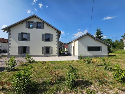 a white house with black windows in a yard at L'Escargot - Maison avec espace bien être in Vagney