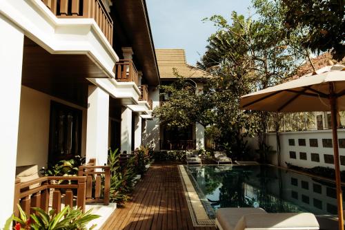 an external view of a house with a swimming pool and an umbrella at Athena Hotel in Pakse