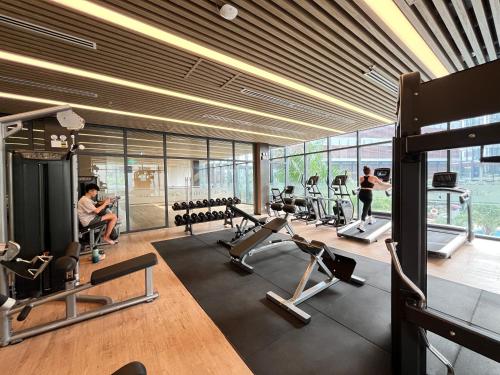 a gym with cardio equipment and people in the background at The Regal Residence at Vinhomes in Ho Chi Minh City