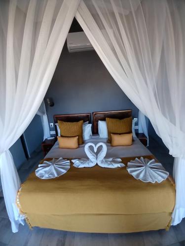 a bedroom with a large bed with white curtains at Mababe River Lodge in Mababe