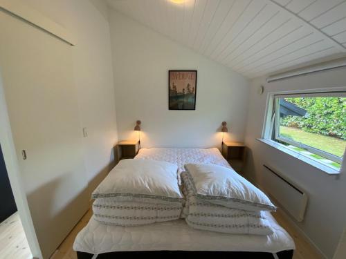 a bedroom with a bed with pillows and a window at Holiday home Ejby Ådal in Kirke-Hyllinge