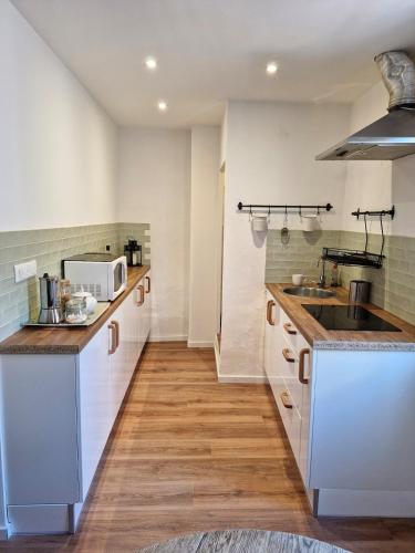 une cuisine avec des armoires blanches et un évier dans l'établissement Charmant appartement, en plein centre historique !, à Avignon