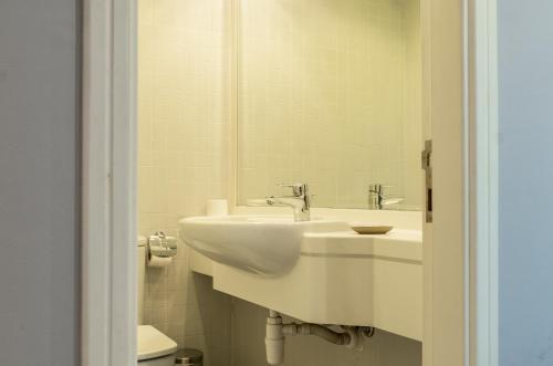 a white bathroom with a sink and a mirror at Lagom Vacation Homes One Bedroom Apartment Al Shera Tower cluster E in Dubai