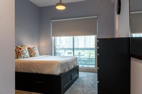 a bedroom with a bed and a large window at Lagom Vacation Homes One Bedroom Apartment Al Shera Tower cluster E in Dubai