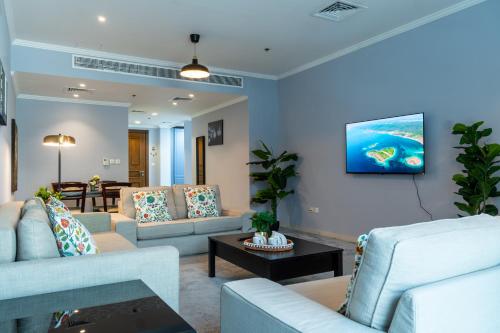 a living room with couches and a tv on a wall at Lagom Vacation Homes One Bedroom Apartment Al Shera Tower cluster E in Dubai