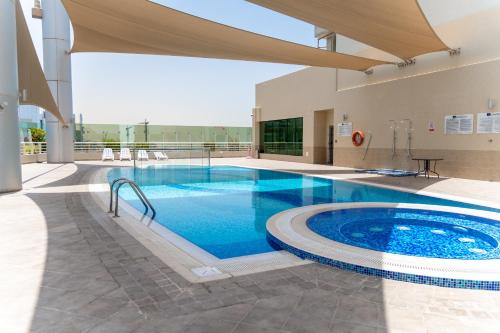 a large swimming pool in a building with a large building at Lagom Vacation Homes One Bedroom Apartment Al Shera Tower cluster E in Dubai