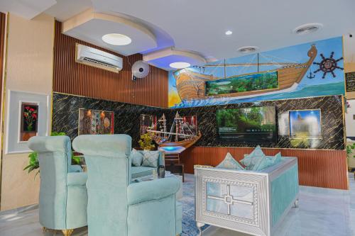 a lobby with two chairs and a painting of a boat at Arkan Al Barzah Hotel Apartment in Sur