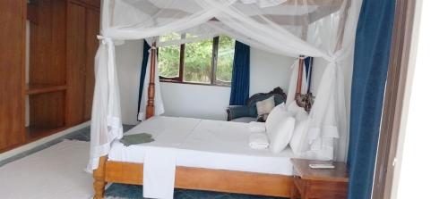 a bedroom with a white canopy bed with a window at Imani holiday homes in Mtwapa
