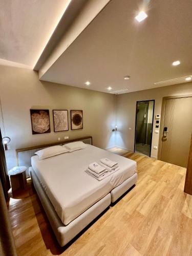 a bedroom with a large white bed and wooden floors at Green Condo Hotel Palase in Palasë