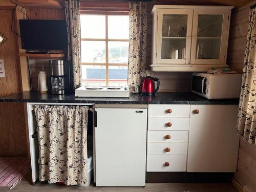 a kitchen with a white refrigerator and a window at Nordnes Kro og Camping in Rokland