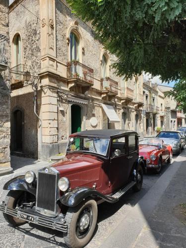 an old red and black car parked in front of a building at Lyberty in Randazzo