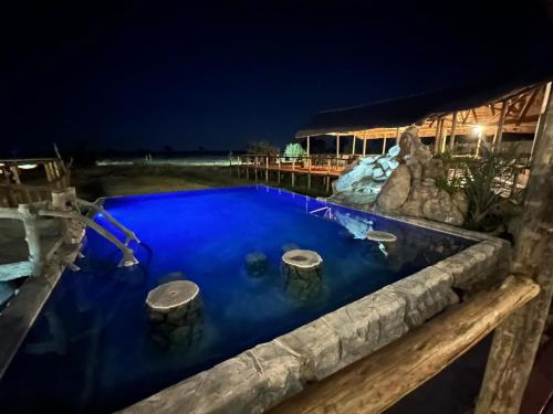 a pool in the middle of a yard at night at Mababe River Lodge in Mababe