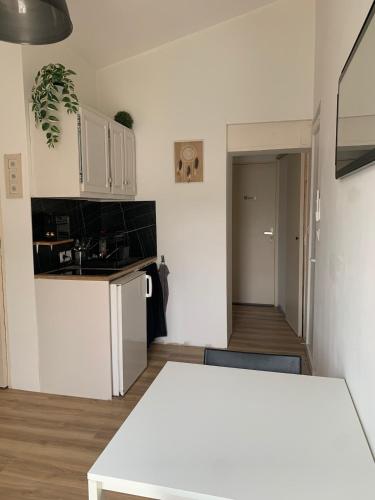 une cuisine avec des armoires blanches et une table blanche dans l'établissement Studio indépendant climatisé, à Saint-Drézéry