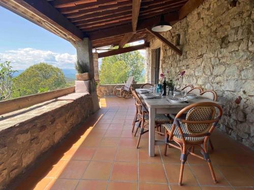 une salle à manger avec une table et des chaises sur un patio dans l'établissement Maison ardéchoise avec panorama, à Sampzon