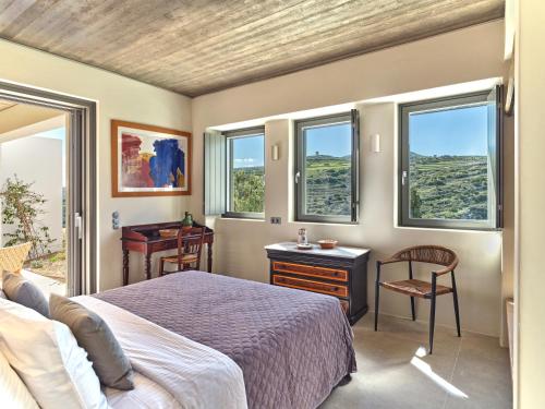 a bedroom with a bed and a desk and windows at Pezoules House II in Lefkes