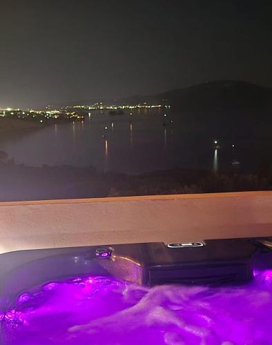 a bath tub with purple lights in front of a window at Athenea Villas, Private Pools & Gardens in Keri