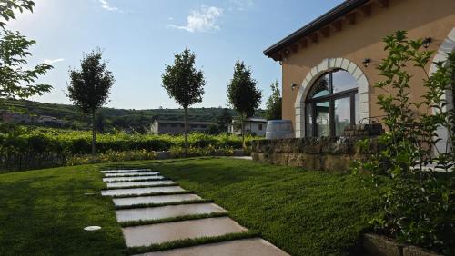 a garden with stepping stones in front of a house at Agriturismo Igino - Camera in Casale con cucina condivisa e spazi comuni, giardino, patio, parcheggio, wineshop, wifi - Immerso nei vigneti in Negrar