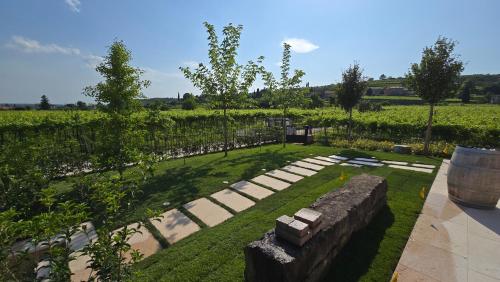 a garden with a stone wall and grass and trees at Agriturismo Igino - Camera in Casale con cucina condivisa e spazi comuni, giardino, patio, parcheggio, wineshop, wifi - Immerso nei vigneti in Negrar