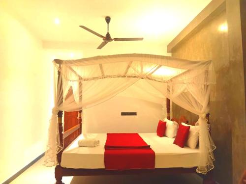 a bedroom with a canopy bed with red pillows at Sea wind in Mirissa