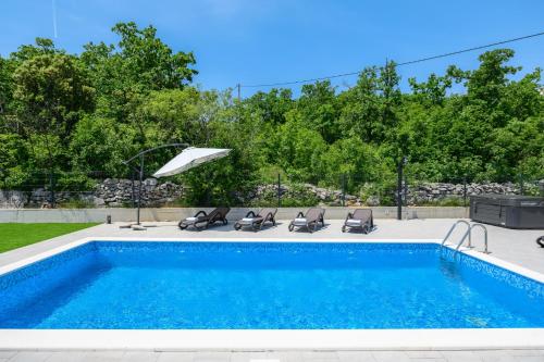 a swimming pool with lounge chairs and an umbrella at Villa Laura by Briskva in Ripenda Kras