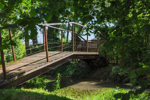 a wooden bridge over a river with trees at Domaine Belle Ombre in Montbellet
