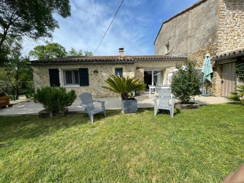 a house with two chairs and a patio at Mas en Pierre "entre Gard et Ardèche" avec jardin in Saint-Victor-de-Malcap