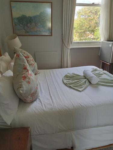 a bedroom with a white bed with pillows and a window at Kardinal guesthouse on 44 St Phillips street in Gqeberha
