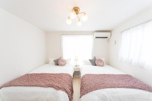 two beds in a room with white walls and windows at Miraie Suzuka Shimomida in Suzuka