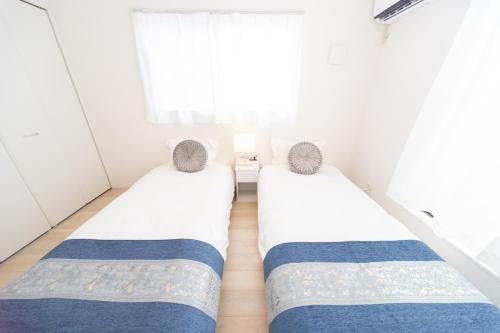 two twin beds in a room with a window at Miraie Suzuka Shimomida in Suzuka