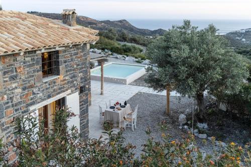 a stone house with a table and chairs and a pool at Palazzo Greco Villas in Agia Galini