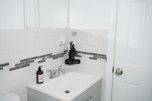 - un lavabo dans la salle de bains avec une bouteille d'alcool dans l'établissement Emerald Room at Brighton Beach 2Min Walk to Ocean n Subway Chic Stay, à Brooklyn