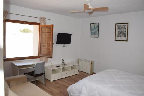 a bedroom with a bed and a desk and a television at EL CHORRO Aire acondicionado Bar privado Barbacoa Amplios patios in Castalla