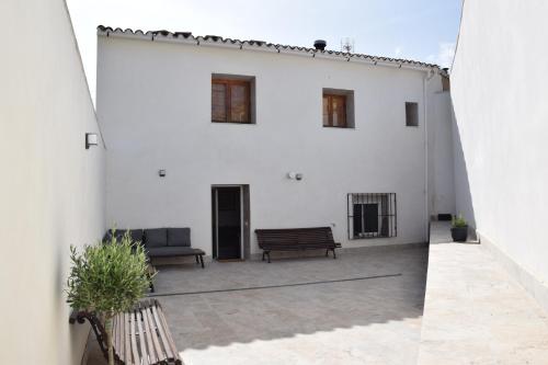 a white building with two benches on a patio at EL CHORRO Aire acondicionado Bar privado Barbacoa Amplios patios in Castalla