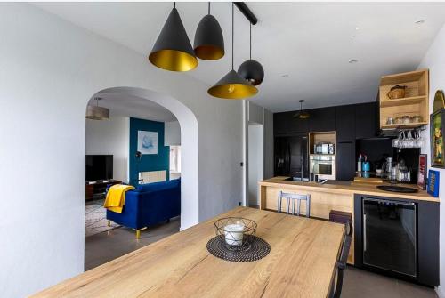 une cuisine et un salon avec une table en bois et des lumières jaunes dans l'établissement Le Collonges - Spacieux Pied à Terre proche Lyon, à Collonges-au-Mont-dʼOr