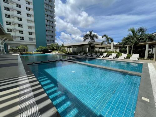 a large swimming pool with chairs and a building at Cozy Studio Condo Bacolod in Bacolod