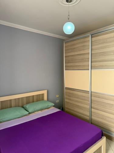 a bedroom with a bed with purple and green sheets at Mateos Apartment Saranda in Sarandë