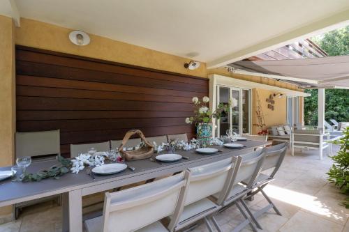 - une grande table avec des chaises, des assiettes et des fleurs dans l'établissement Maison de Famille à la Plage, à La Croix-Valmer