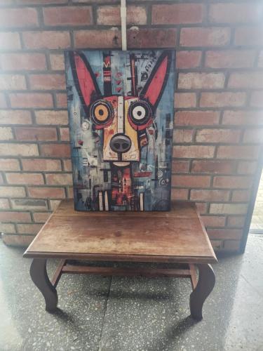 a painting of a dog on a table next to a brick wall at Mount Rd Ocean View in Gqeberha