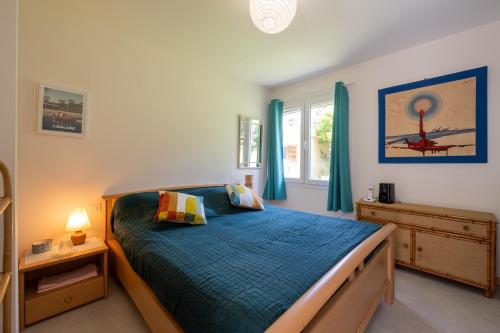 une chambre avec un lit avec des draps bleus et une fenêtre dans l'établissement Maison de Famille à la Plage, à La Croix-Valmer