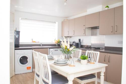 a white kitchen with a white table and chairs at Luxe stylish stay in central Manchester in Manchester