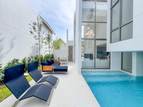 a house with a swimming pool and blue chairs at Modern 3BR Pool Villa near Laguna- Lux Pride 4 by Warm Plus in Ban Pak Lak