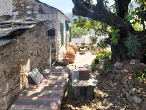a stone house with a stone wall and a tree at Stoneworld in Évdhilos