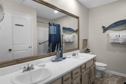 a bathroom with two sinks and a mirror and a toilet at Beach Rendezvous in Navarre